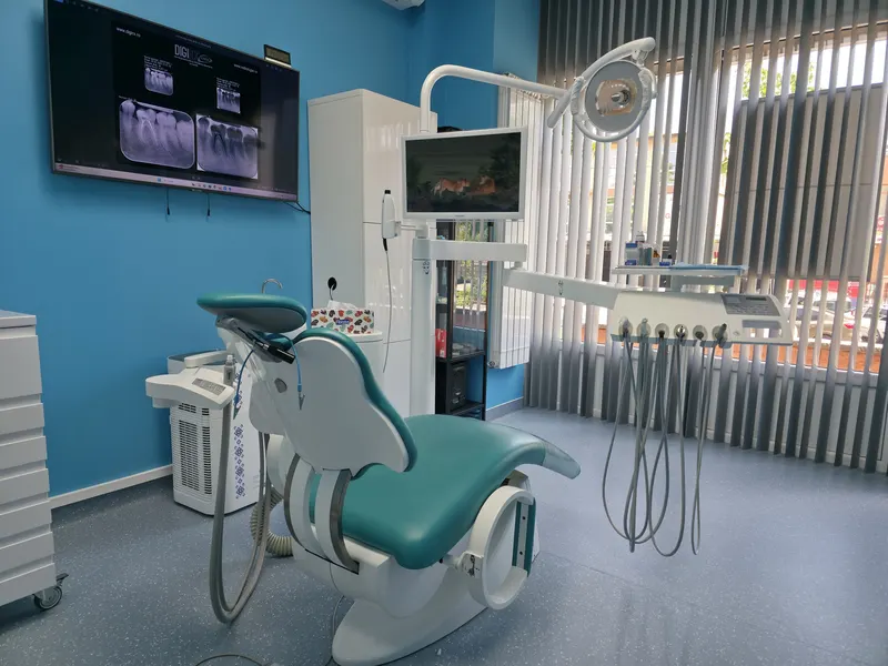Unit dentar turcoaz lângă fereastră, cu o radiografie afișată pe ecran