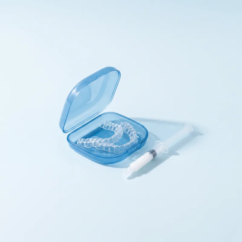 Gutiere transparente de albire într-o cutie, lângă o seringă cu gel