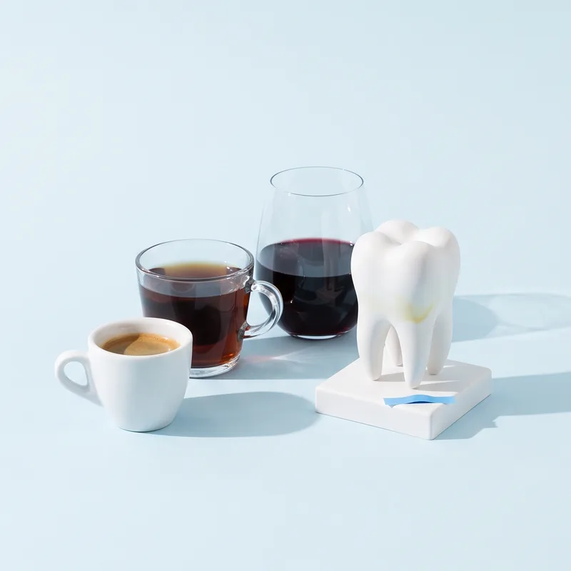 Cafea, ceai și vin roșu lângă un model de dinte cu o ușoară pată