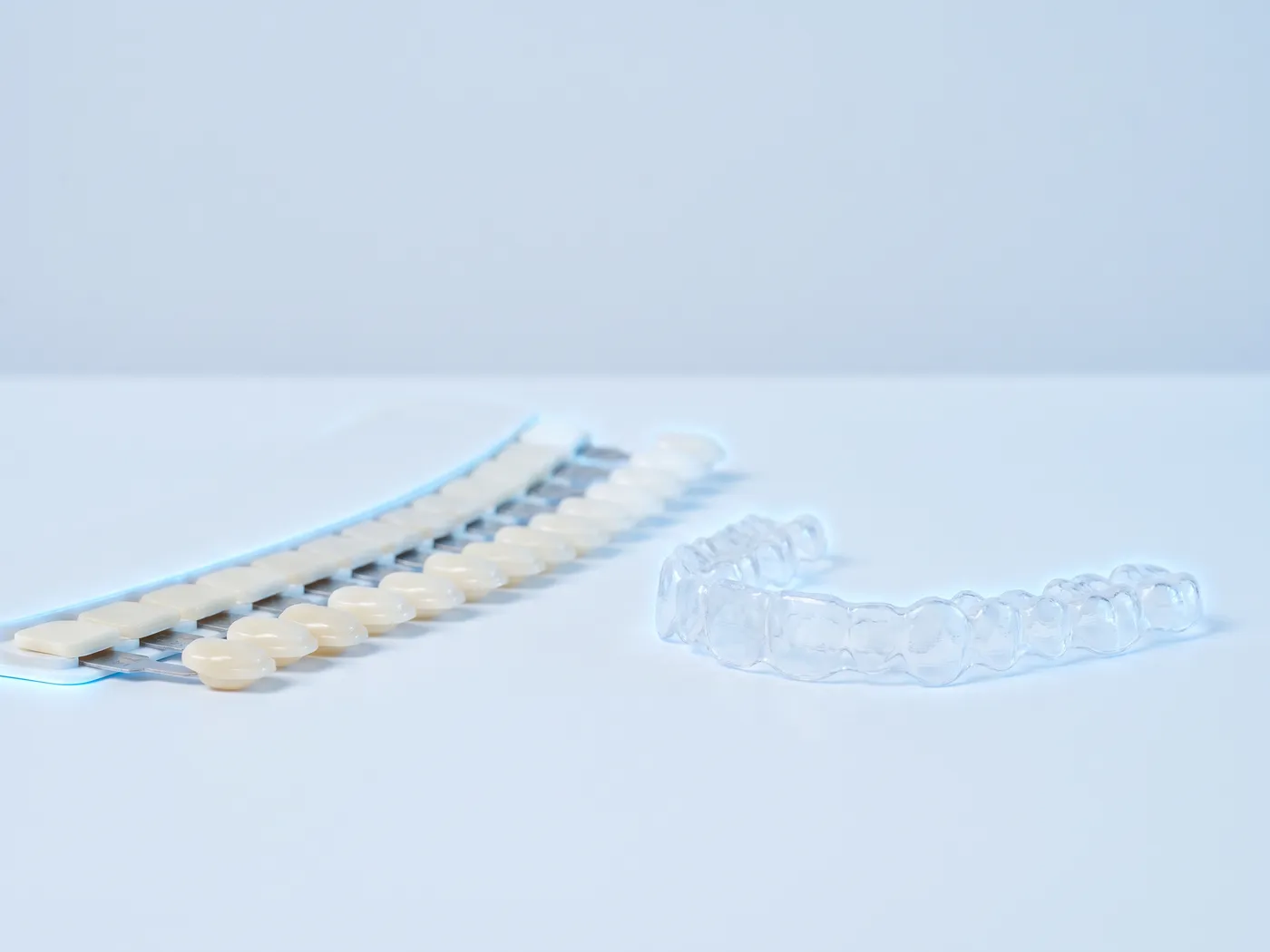 Cheie de culori dentare, de la ivoriu la alb, lângă o gutieră transparentă de albire